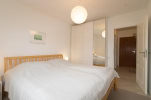 a bedroom with a white bed and a bathroom at Ferienwohnung Strandrose in Hörnum
