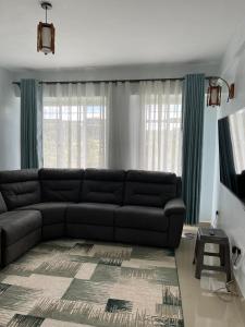 a living room with a black leather couch in front of a window at Zoe Homes 1br and 2br Apartment Greypoint 406 in Kericho