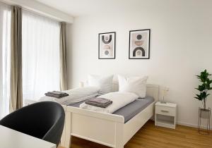 a white bedroom with a bed and a window at Moderne Apartments im Herzen der Stadt I private Tiefgarage mit Ladesäulen I home2share in Ibbenbüren