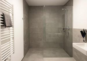 La salle de bains est pourvue d'une douche et d'un lavabo. dans l'établissement Moderne Apartments im Herzen der Stadt I private Tiefgarage mit Ladesäulen I home2share, à Ibbenbüren