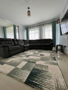 sala de estar con sofá negro y alfombra en Zoe Homes 1br and 2br Apartment Greypoint 406 en Kericho