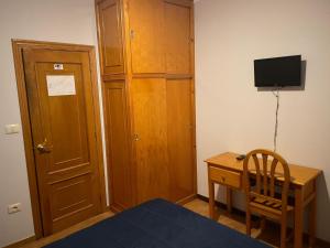 1 dormitorio con armario de madera y escritorio con TV en HOSTAL CID en Ourense