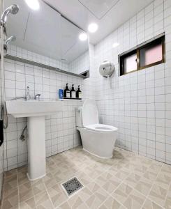 a white tiled bathroom with a toilet and a sink at Sinchon station 4 min three-room hongdae in Seoul
