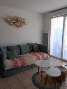 a living room with a green couch and two tables at Mignon appartement en résidence avec piscine in Biscarrosse