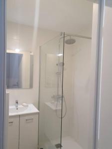 a white bathroom with a shower and a sink at Mignon appartement en résidence avec piscine in Biscarrosse