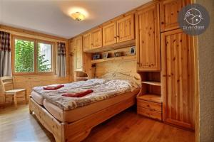 a bedroom with a large bed with wooden cabinets at Rhodos Confort et Qualité in Ovronnaz