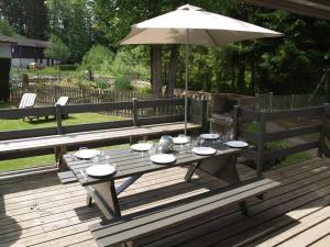a picnic table with an umbrella on a deck at Chalet Balthazar in Durbuy