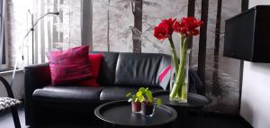 a black couch with a vase of red flowers on a table at Vakantiehuis It Loazjemint in Oostermeer