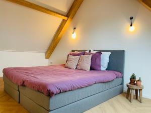 a bedroom with a bed with purple sheets and pillows at 't Soute Land in Zoutelande