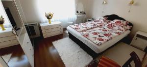 a small bedroom with a bed with red and white sheets at Nyaralóház HANGA in Fonyód