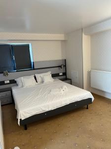 - une chambre dotée d'un grand lit avec des draps et des oreillers blancs dans l'établissement Noblesse Bacău, à Bacău