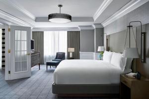 ワシントンにあるザ リッツ カールトン ワシントン D.C.の大きなベッドと椅子が備わるホテルルームです。