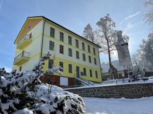 a yellow building with snow in front of it at Moderní apartmán uprostřed šumavské přírody in Zdíkovec