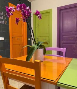 una mesa con un jarrón con flores púrpuras. en B&B Sangro, en Atessa