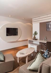 een woonkamer met een tafel en een tv aan de muur bij Hotel Villa Lago Garni in Bad Wiessee