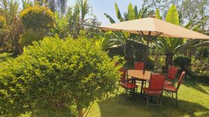 einen Tisch und Stühle mit Sonnenschirm in einem Garten in der Unterkunft Homebase gardens in Nakuru