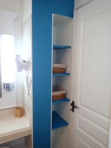 uma casa de banho com prateleiras azuis ao lado de uma porta em Antigua 04 em Sainte-Luce
