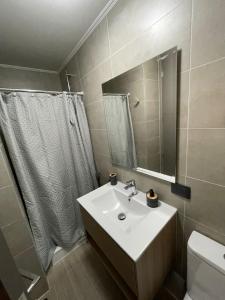 a bathroom with a sink and a toilet and a mirror at Pucón Estilo Resort in Pucón