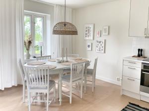 una cucina con tavolo da pranzo e sedie di Boende med pool och tennisbana i familjevänligt område a Torekov