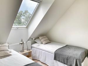 a attic bedroom with two beds and a window at Boende med pool och tennisbana i familjevänligt område in Torekov