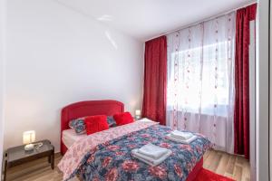 a bedroom with a bed with red pillows and a window at Apartman Vedro Polje in Gospić