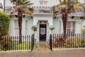 a white house with palm trees in front of a gate at Princes Villa - large fully Self Contained Flat, 5 minutes from the sea in Hastings