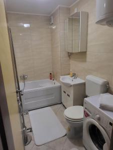 a bathroom with a toilet and a sink and a washing machine at OPTIMUM 2 - One bedroom apartment in Zenica