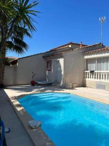 a blue swimming pool in front of a house at Maison avec piscine privée in Le Grau-du-Roi