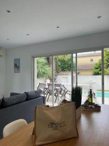 a living room with a couch and a table with a bag at Maison avec piscine privée in Le Grau-du-Roi