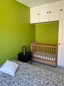 - une chambre avec un lit bébé et un mur vert dans l'établissement Maison avec piscine privée, au Grau-du-Roi