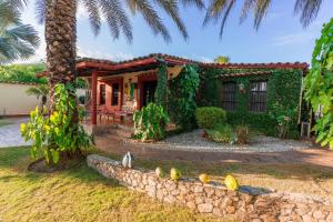 a house with a palm tree and a stone wall at Villa Cococaribic Isla Margarita Venezuela in Paraguchi