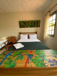 ein Schlafzimmer mit einem Bett mit einer bunten Decke darauf in der Unterkunft Pousada Artes Evano in Bichinho