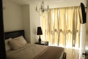 Un dormitorio con una cama y una ventana con una lámpara de araña. en Alquiler Apto Ibiza Playa Corona- Reserva mínimo 2 noches, en Copecito