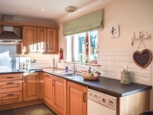 a kitchen with wooden cabinets and a sink and a window at Trelaw in Ochiltree