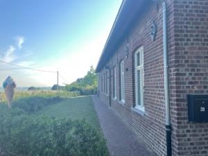 a red brick building with a sidewalk next to it at Velogement 't Moltje in Heuvelland