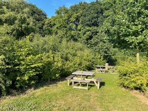 a picnic table and bench in a field with trees at Velogement 't Moltje in Heuvelland