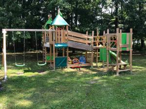 a wooden playground with a slide and swings at Seeblick eins im Waldschlößchen in Wendisch Rietz