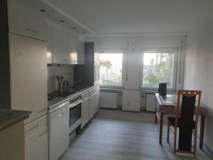 a kitchen with white cabinets and a table and a dining room at Haus am Hang, Garden Dream in Westerburg