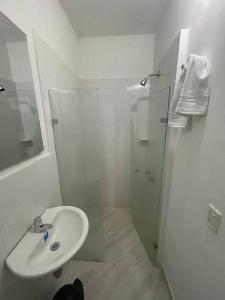 y baño blanco con lavabo y ducha. en Aparta-hotel laureles 201, en Medellín