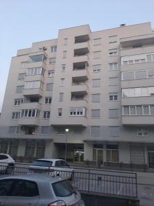 Apartment Mija-Meri في توزلا: عمارة سكنية كبيرة فيها سيارات تقف امامها