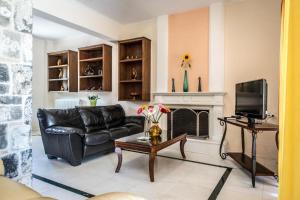 a living room with a black leather couch and a fireplace at Erodios Villas 2 in Ptinotrofíon