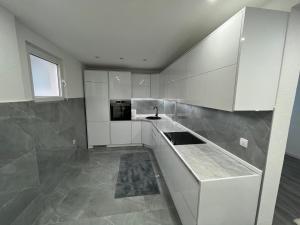 a kitchen with white cabinets and a sink at Apartman Bajo 1 in Foča