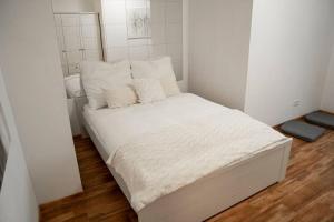 - duże białe łóżko w pokoju z drewnianą podłogą w obiekcie Ferienwohnung in der Nähe von Köln w mieście Frechen