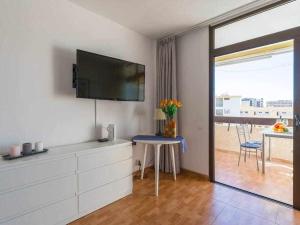 a living room with a tv and a table with flowers at Marlenghi Apartments 412 in San Bartolomé de Tirajana