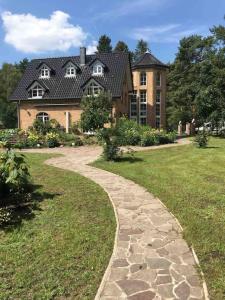 a stone path in front of a large house at Seeblick zwei im Waldschlößchen in Wendisch Rietz