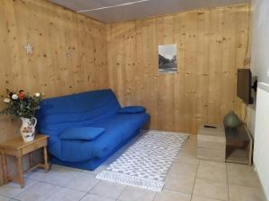 ein blaues Sofa in einem Zimmer mit Holzwänden in der Unterkunft Appartement dans un chalet de montagne in Guillestre