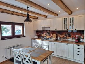 a kitchen with white cabinets and a wooden table at Apartamenty Pod Lipą in Lutowiska