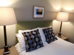 um quarto com 2 candeeiros e uma cama com almofadas em Raasay House Hotel em Raasay