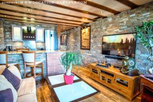 a living room with a tv and a brick wall at Location de charme de Thierry BOURGAIT in Banyuls-sur-Mer