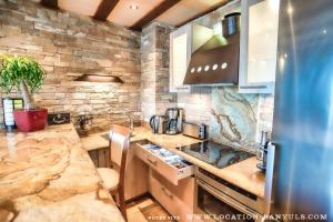 a large kitchen with a stone wall at Location front de mer de Thierry Bourgait in Banyuls-sur-Mer